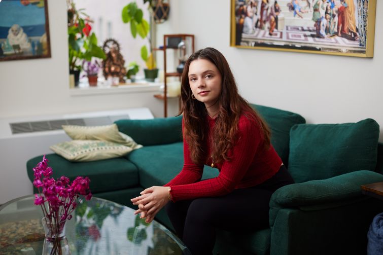 A woman sitting on a couch with her hands folded.