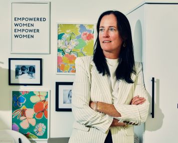 A woman with her arms folded, leaning against a wall.
