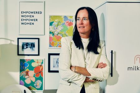 A woman with her arms folded, leaning against a wall.