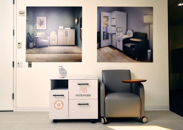 A small table with drawers next to a cushioned chair with a side table built into it. 