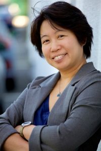 A woman, arms folded and smiling. 