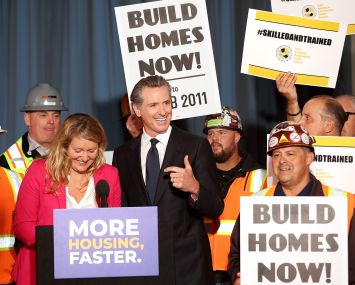 California Gov. Gavin Newsom (C) points to California Assemblymember Buffy Wicks (L) during a press conference.