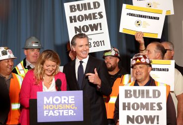 California Gov. Gavin Newsom (C) points to California Assemblymember Buffy Wicks (L) during a press conference.