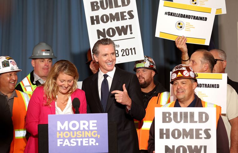 California Gov. Gavin Newsom (C) points to California Assemblymember Buffy Wicks (L) during a press conference.