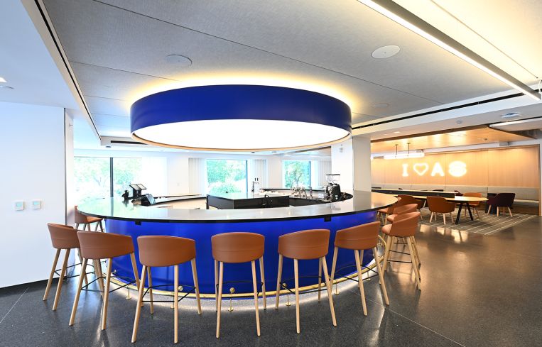 A row of bar stools surrounding a circular blue counter.