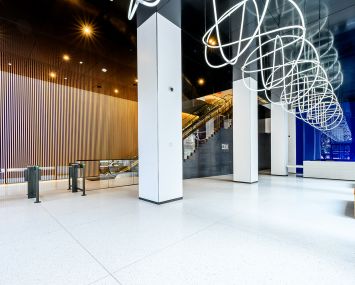 A private lobby with white tiles and a coiled white tube hanging overhead.
