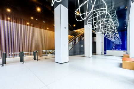 A private lobby with white tiles and a coiled white tube hanging overhead.