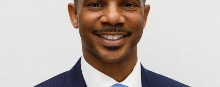 A man in a suit, smiling.