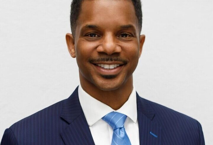 A man in a suit, smiling.