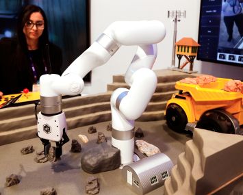 A woman operating a small robot on a table.