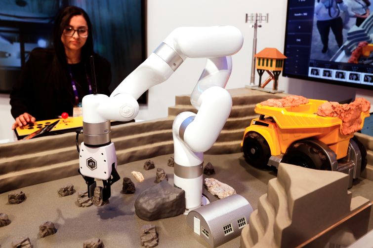 A woman operating a small robot on a table.