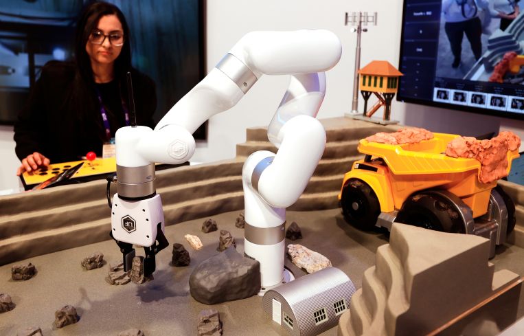 A woman operating a small robot on a table.