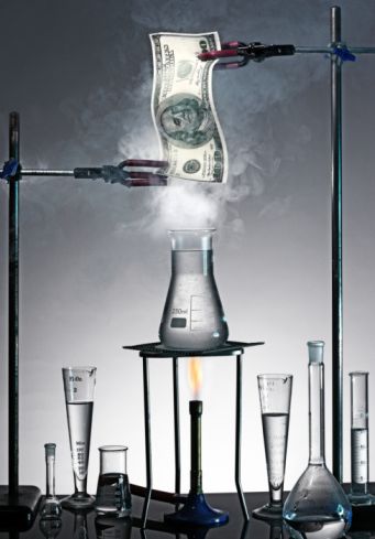 Image of a dollar bill being set on fire over a beaker.