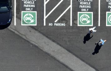 An aerial view of an electric vehicle charging station with pedestrians walking.