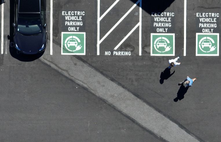 An aerial view of an electric vehicle charging station with pedestrians walking.