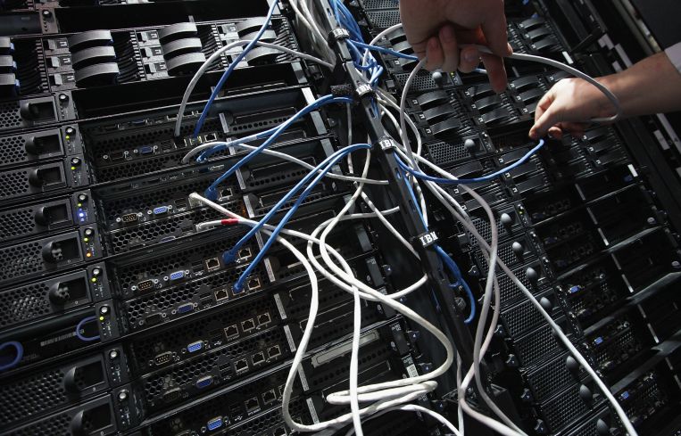 A photo of hands connecting wires in a data center.