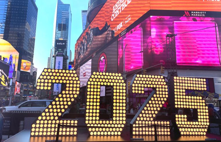 A lighted-up 2025 sign on an urban street.