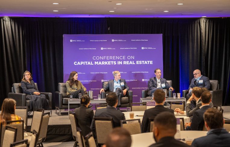 A photo of people sitting at a real estate pannel.