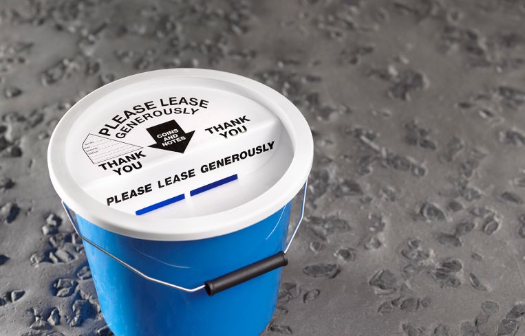 Charity collection bucket that read "Please Lease Generously."