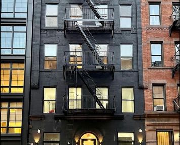 Photo of a small building with a fire escape in front.