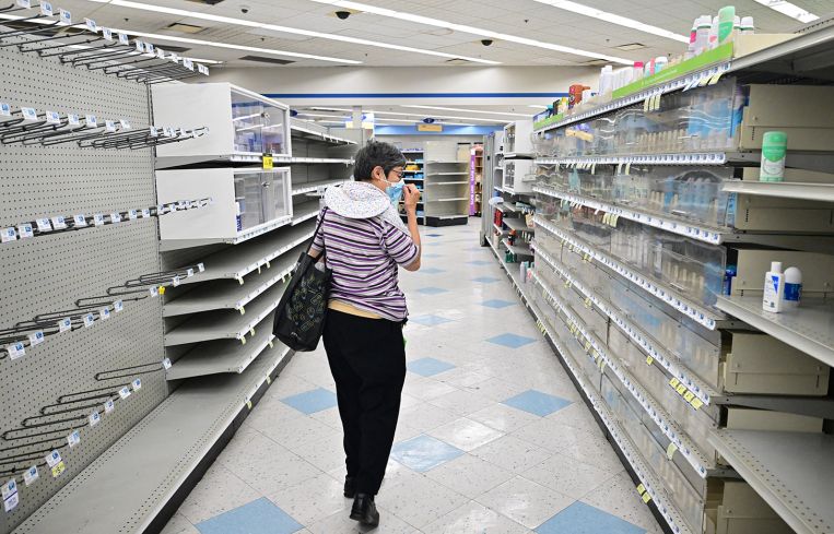 A woman browses through what items remain on near empty shelves at a pharmacy.