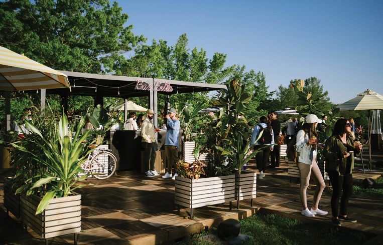 People milling around a bar outside.