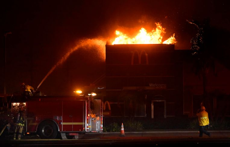 Firefighters try to extinguish the flames as a McDonalds burns at the corner of Altadena Drive and Washington Boulevard during the Eaton Fire in Pasadena.