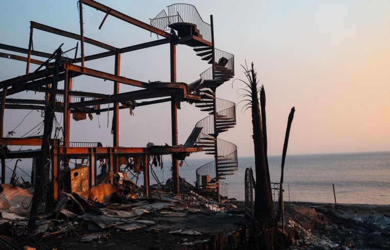 A spiral staircase stands amidst the smoldering skeleton of a house destroyed by the Palisades fire along the Pacific Coast Highway in Malibu.