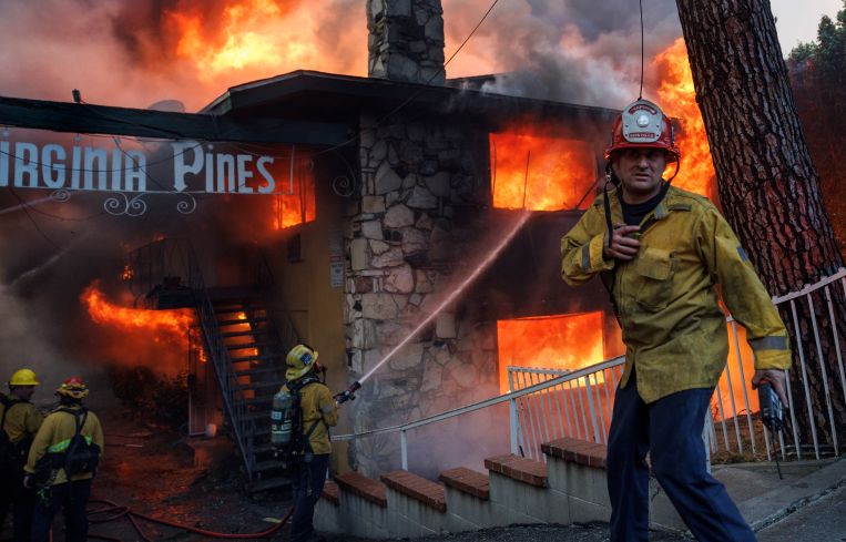 A Kern County fire captain directs his crews who are fighting an intense apartment fire blaze fueled by heavy winds from the Eaton fire on East Pine Street in Altadena, California.