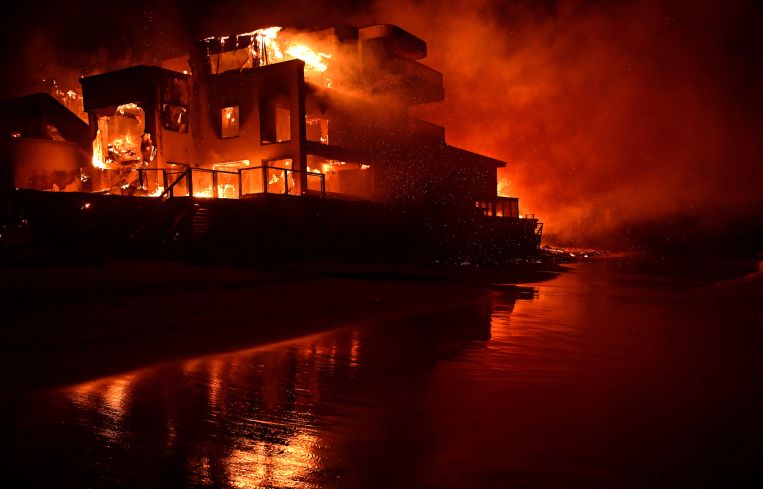 A beach house is engulfed in flames as the Palisades Fire burns along Pacific Coast Highway in Malibu.
