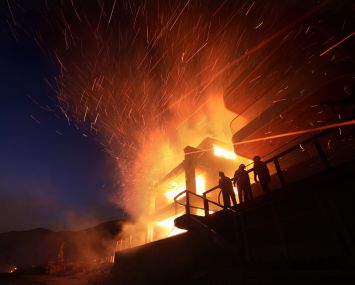 A firefighter battles a house fire along PCH as the Palisades Fire burns in Malibu.