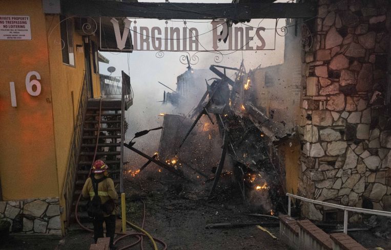 The right side of the Virginia Pines Apartments building crashes to the ground after burning entirely from the Eaton Fire.