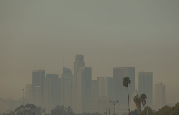 Wildfire smoke from the Palisades and Eaton fires blankets a view of downtown Los Angeles as well as Los Angeles County, prompting school closures and triggering air quality advisories across the region.