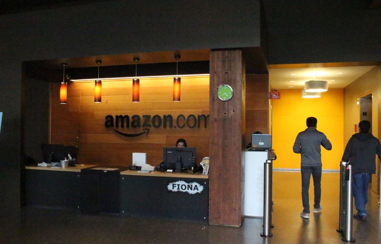 A lobby of an office with people and a sign that reads Amazon.