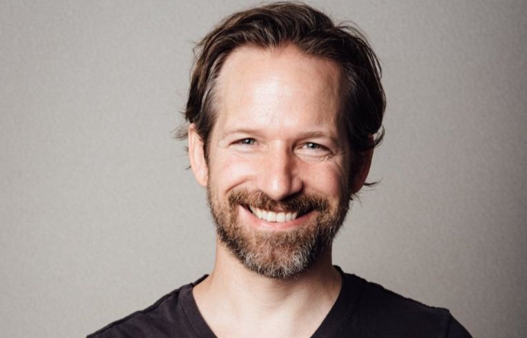 A man in a t-shirt, smiling.