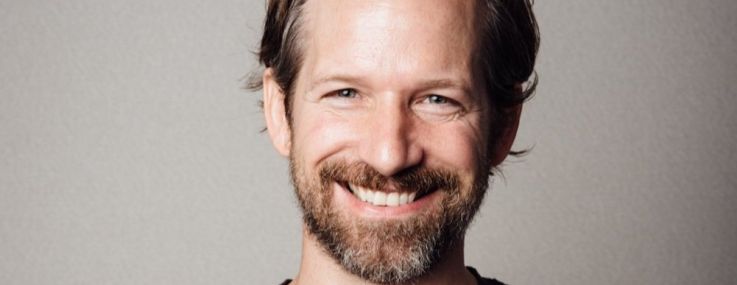 A man in a t-shirt, smiling.