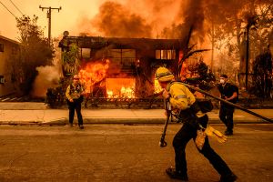 Firefighters pull a hose to an apartment building buring in the L.A. wildfires.