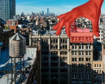 A hand reaching out of the sky and lifting part of a building away.