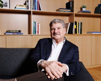 A man seated in front of a bookshelf.