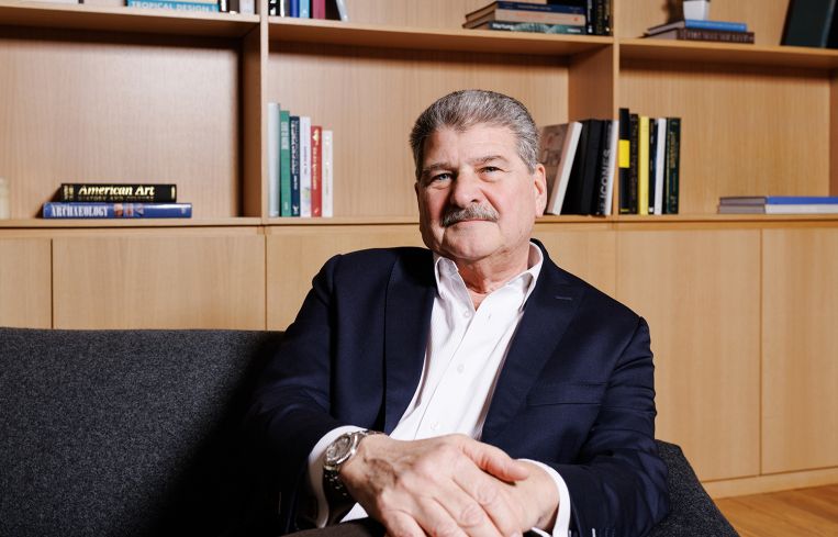 A man seated in front of a bookshelf.