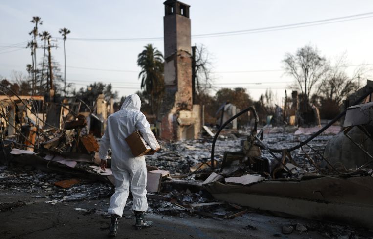 Aviana Springs carries away a box containing jars of ashes she collected from the remains of Altadena United Methodist Church which burned in the Eaton Fire in Altadena, California.