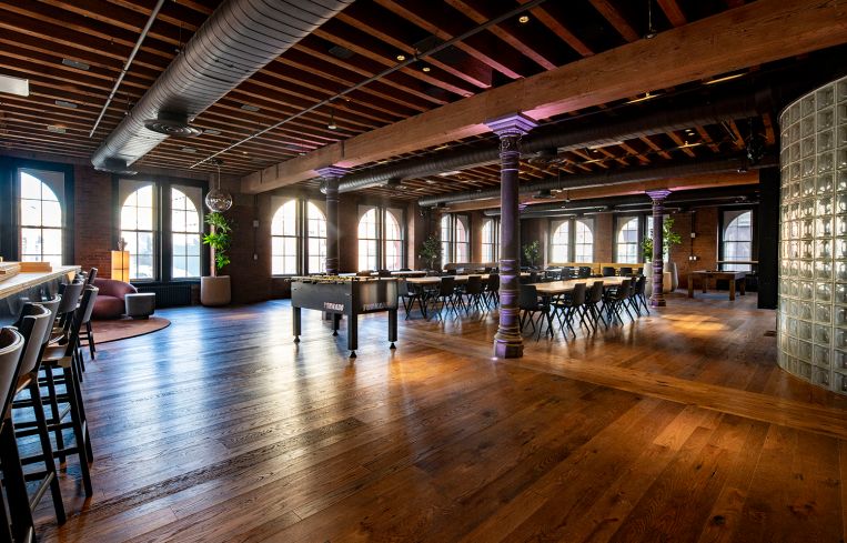 An expansive office floor with a table in the middle and high ceilings.