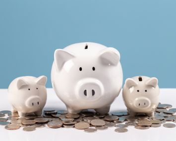 Family piggy bank, white ceramic piggy bank on stack coins on white wood table, saving money, financial planning.