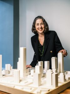 A woman standing over a model of a skyline. 