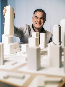 A man squatting behind a model of a skyline. 