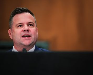 A man's head at a table, speaking.