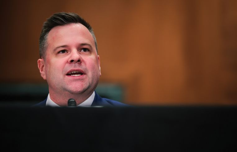 A man's head at a table, speaking.
