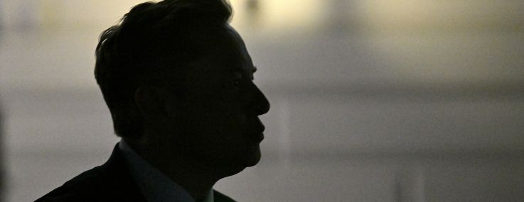 Elon Musk is silhouetted as he departs the White House.