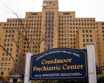 A looming building with a sign that says Creedmoor Psychiatric Center in front of it.