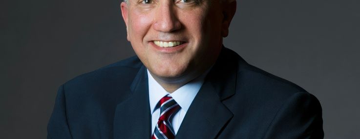 A man in a suit smiling.